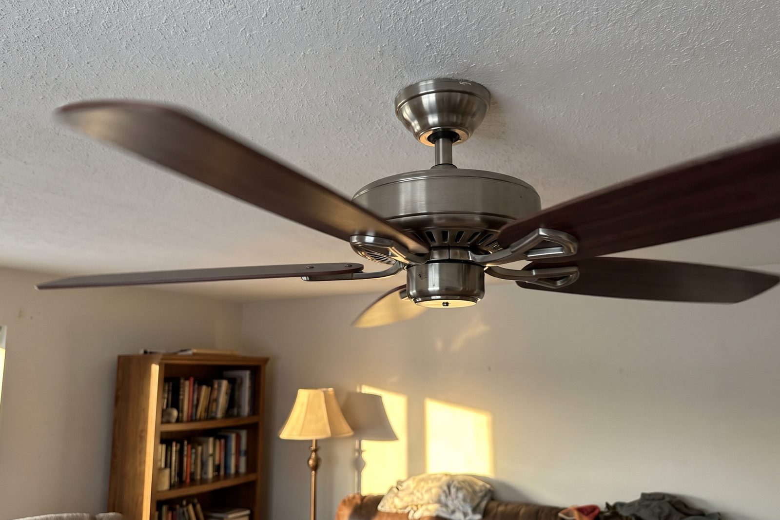 The canopy and downrod of a ceiling fan turning in a lived-in living room