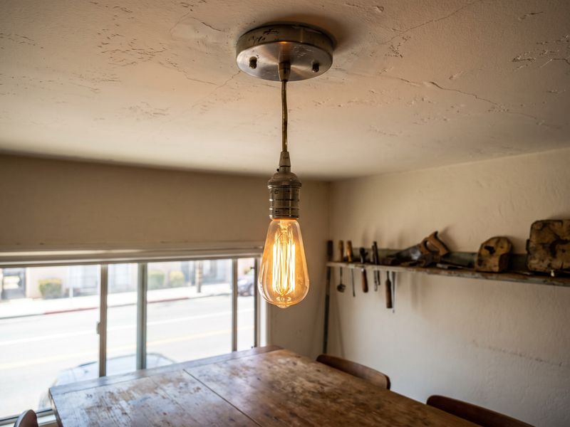 A pendant light fitted over a dining table, warm bulb lit