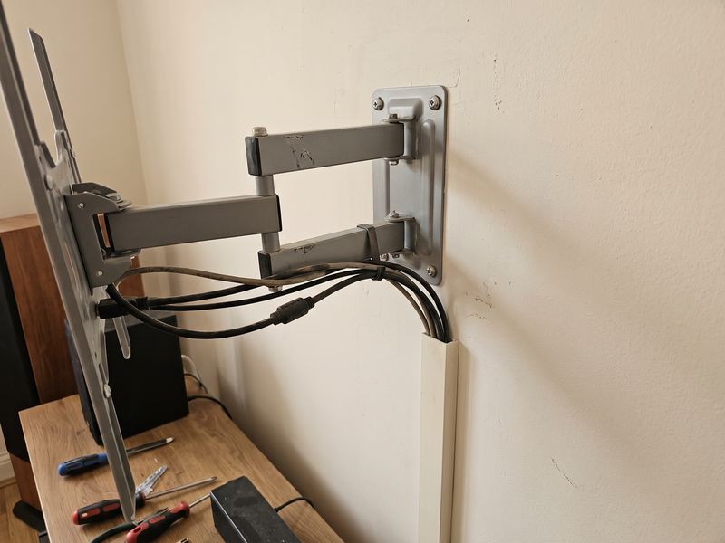 A television bracket bolted flat to a wall with the cable run into a slim raceway